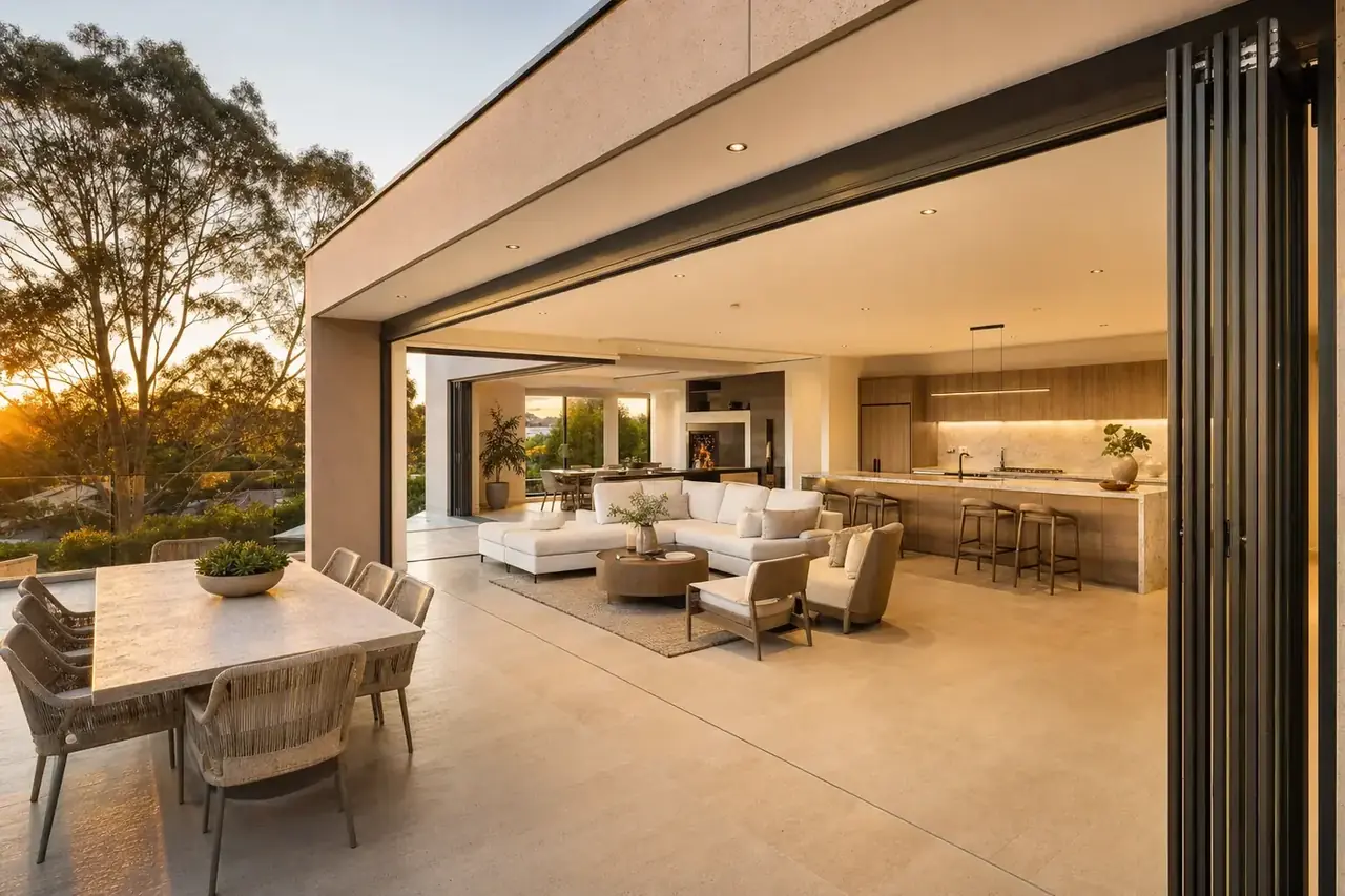 Black aluminium bifold doors folded right back to open a kitchen onto a terrace